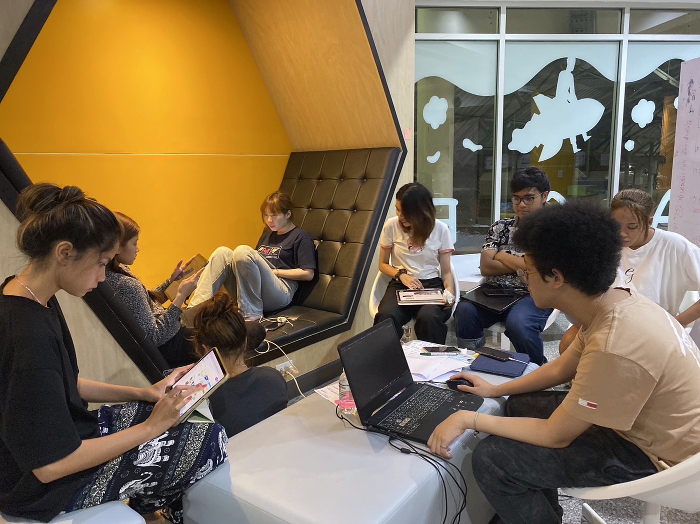 InnoEM students collaborating on laptops in the building's lounge workspace